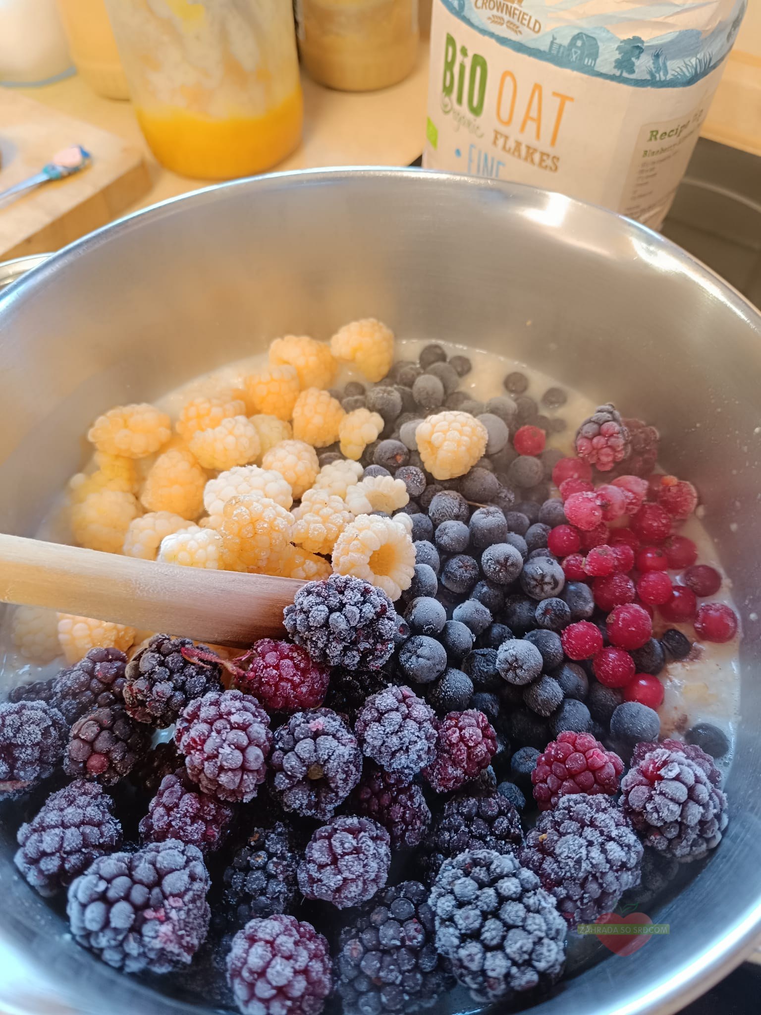 Permakultúrny jedlý les v záhrade so zmiešanou výsadbou stromov, kríkov a bylín a miska s domácim mrazeným ovocím.